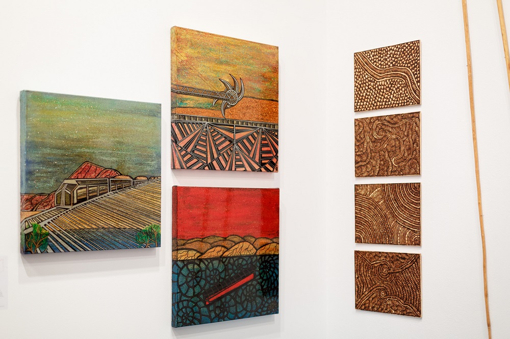 Works left to right: Adina Newman (Spinifex Hill Artists), 2016, acrylic, glitter and lacquer on canvas, dimensions variable; Cynthia Burke (Maruku Arts & Crafts), Ngayuku Ngurra (Walka Boards Landscape), 2017, burnt etching on plywood, 40 x 30cm (4 panels). Photography by Jessica Wyld