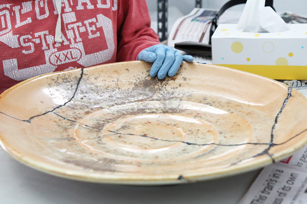 Artist in Residence Stephanie Hammill with a large broken plate that she is repairing using the Kintsugi technique