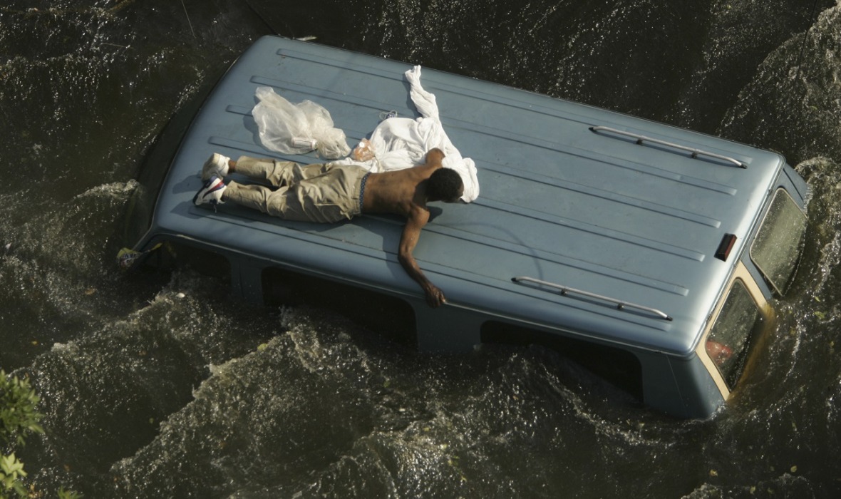 A man clings to the top of a vehicle before being rescued by the U.S. Coast Guard from the flooded streets of New Orleans, in the aftermath of Hurricane Katrina, in Louisiana September 4, 2005. Image copyright Reuters. Photography by Robert Galbraith