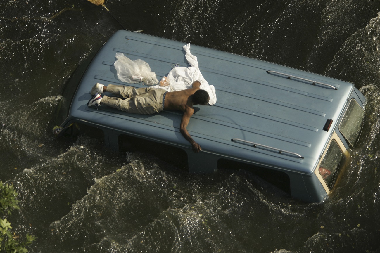 A man clings to the top of a vehicle before being rescued by the U.S. Coast Guard from the flooded streets of New Orleans, in the aftermath of Hurricane Katrina, in Louisiana September 4, 2005. Image copyright Reuters. Photography by Robert Galbraith